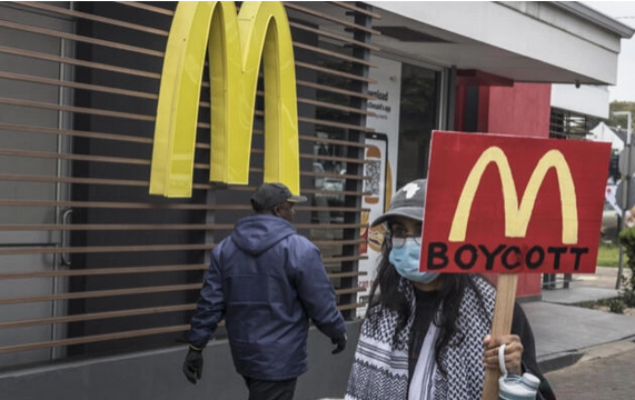Un manifestante sostiene un cartel llamando al boicot de McDonalds