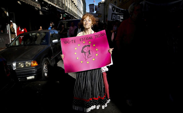 Una mujer sujeta en Lisboa un cartel cuyo lema reza: "¡Troika, que te jodan!"