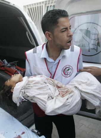 Un trabajor médico lleva en brazos a uno de los cuatro niños muertos por un ataque del Ejército israelí.