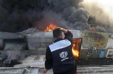 Un trabajador local de Naciones Unidas mira el fuego en la sede de la ONU tras el bombardeo israelí.