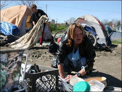 Carol Carlile frega algunos platos en uno de los campamentos de Sacramento de 'sin techo'