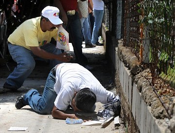 También persiguen al pueblo. Manifestantes hondureños se protegen detrás de una pequeña pared para cubrirse de los disparos de los soldados en las cercanías del Palacio Presidencial en Tegucigalpa este 28 de Junio 2009