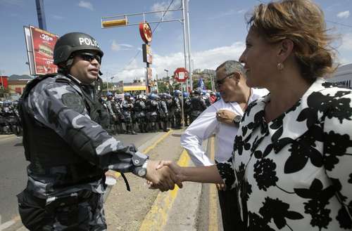Xiomara Castro, esposa del presidente constitucional de Honduras, Manuel Zelaya, saluda a un oficial tras participar en una marcha de la resistencia