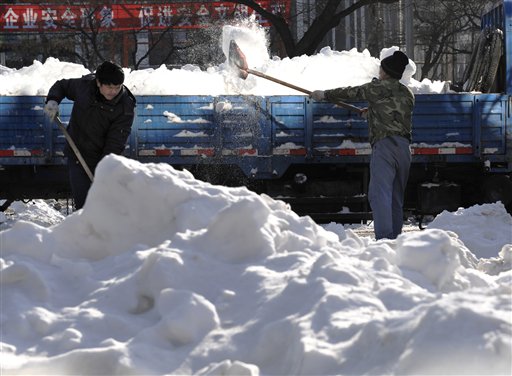 Empleados municipales palean nieve en una calle en el centro de Beijing el martes