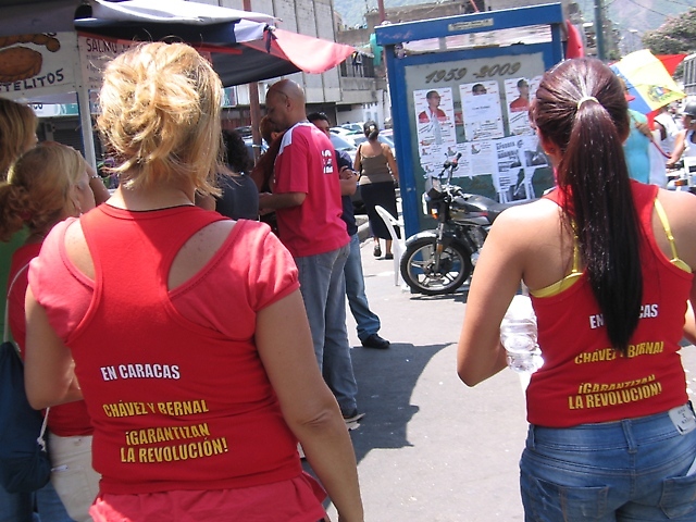 Personas pertenecientes al comando de campaña de Freddy Bernal portando camisas de la candidatura en la acera frente al centro de votación