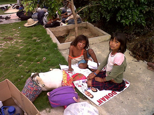 Niños y niñas indígenas sentados encima de la política (afiches electorales que consiguieron en los alrededores)