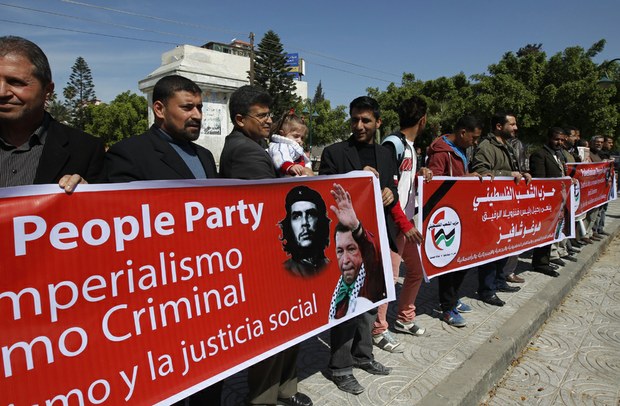 Palestinos sostienen una pancarta con slogans y pinturas de Chávez en Gaza