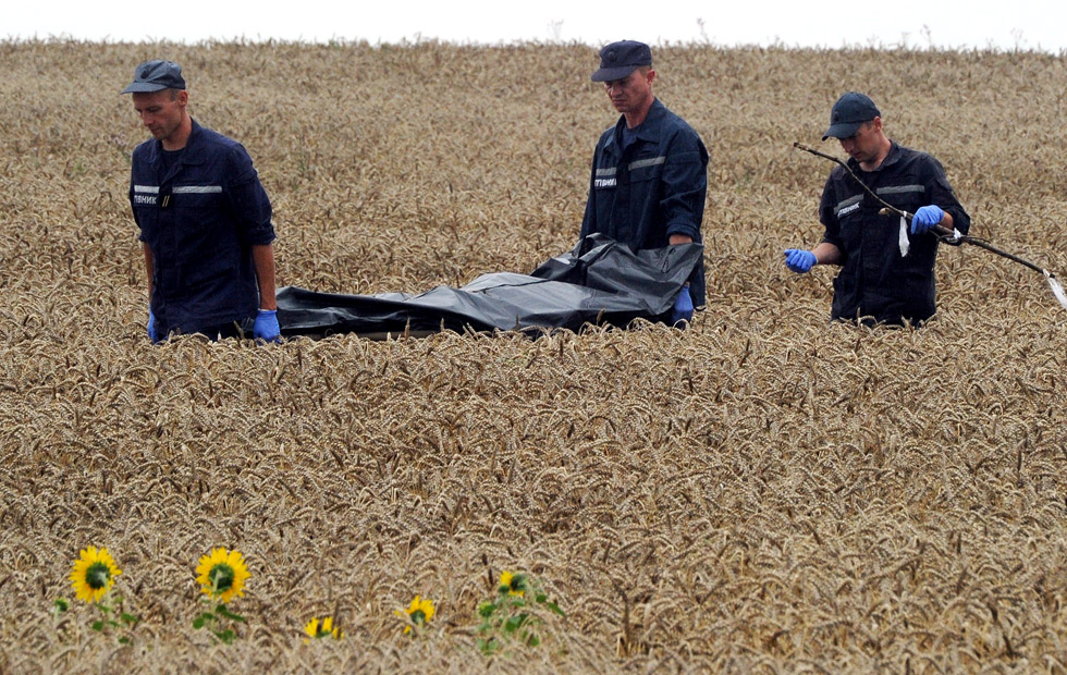 Personal de emergencias trasladan el cadáver de uno de los pasajeros del avión malasio derribado