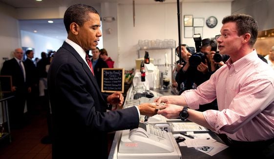 Obama recibe su vuelto luego de pagar en efectivo su comida y la de Joe Biden en un restaurant de hamgurguesas en Arlington, Virginia en 2009