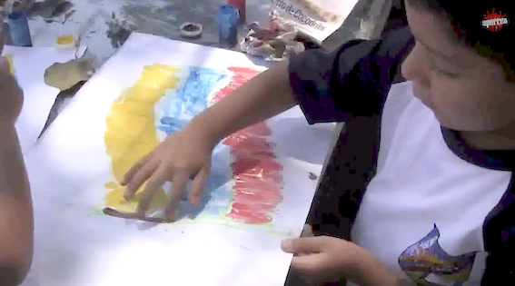 Este niño en plena actividad pintando la bandera de la República Bolivariana de Venezuela con sus ocho estrellas