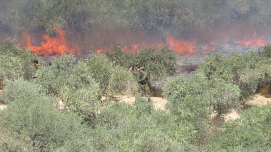 Soldados israelíes sacan fotos de un incendio provocado por colonos israelíes en la ciudad cisjordana de Burin, 14 de octubre de 2015.