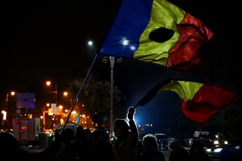 Manifestantes contra la corrupción muestran banderas de Rumanía cortadas.