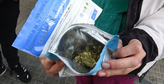 Un hombre muestra un sobre con marihuana comprada en una farmacia de Montevideo