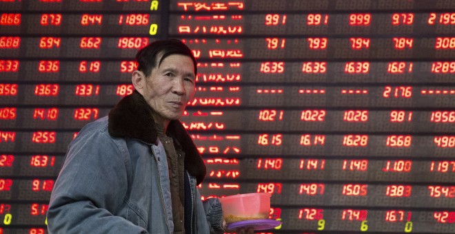 Un hombre pasa por delante del panel que muestra información de los mercados, en un firma de bolsa en la ciudad china de Nanjing. REUTERS/China Daily