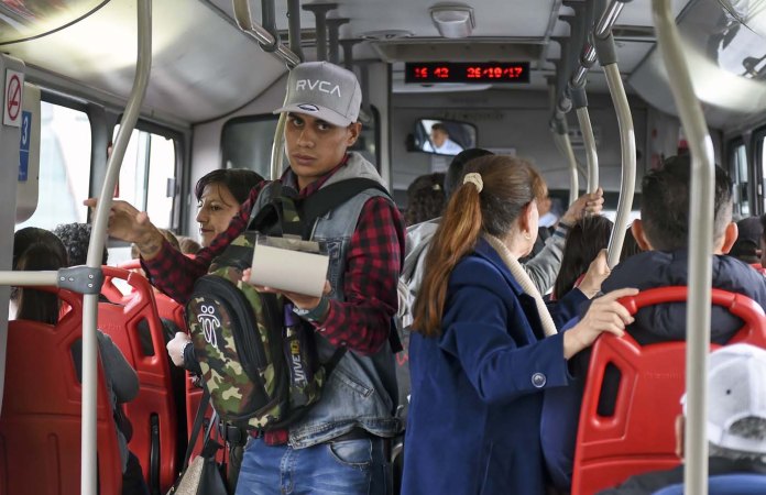 Jhonger Pina, 25, vende caramelos y muestra como curiosidades los billetes de 50 y 100 bolívares en un autobús en Bogotá