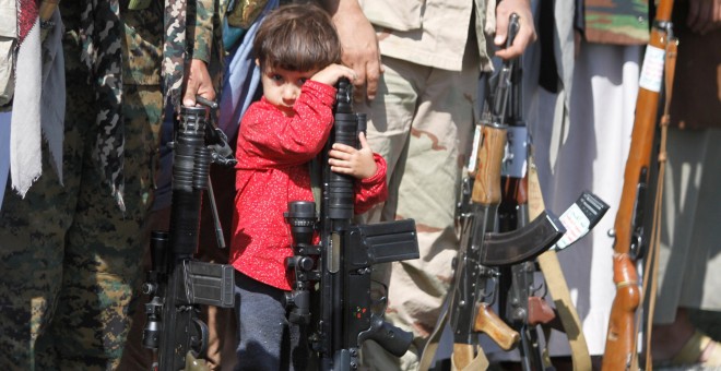 Un niño descansa apoyado sobre un arma en Yemen.
