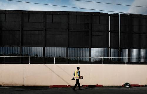 Un trabajador de la ciudad de Brownsville, Texas, limpia un área bajo el muro fronterizo