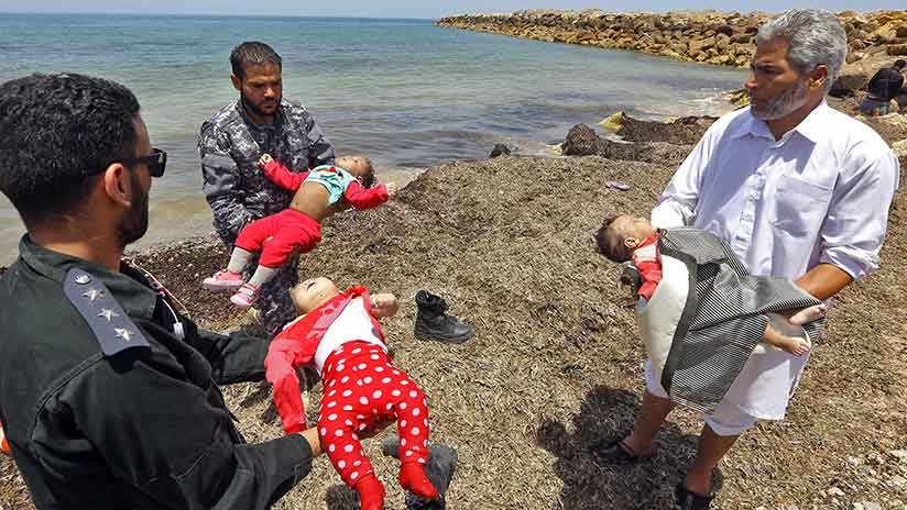 Miembros de las fuerzas de seguridad libias sostienen los cadáveres de tres bebés fallecidos en el naufragio frente a la costa de Libia, el 29 de junio de 2018