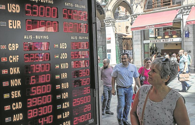 Mujer observa a cómo se intercambia la lira turca en un puesto de cambio de divisas en Estambul