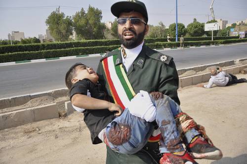 Un soldado traslada a un niño que resultó herido durante un ataque terrorista contra un desfile militar en Irán.