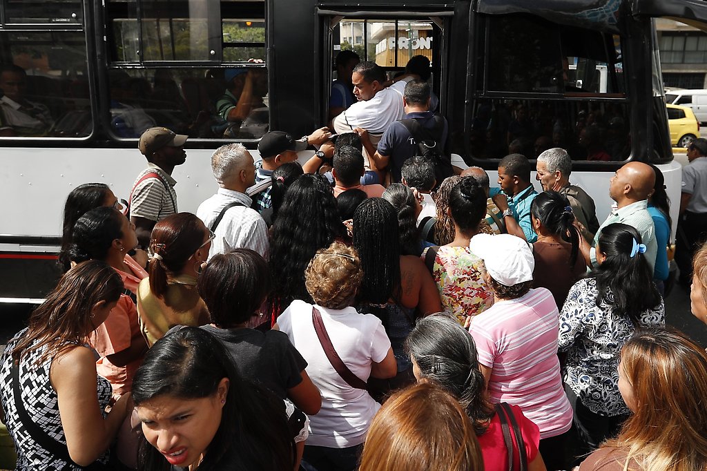 Pasajeros se apresuran para abordar un autobús este jueves en Caracas
