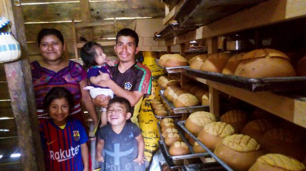 El indígena ixil Diego Matom posa satisfecho junto a su familia, rodeado de panes recién horneados, gracias a generación comunitaria de electricidad, que ha mejorado notablemente su negocio, en la comunidad 31 de Mayo, en la montañosa ecorregión de Zona Reina, en el noroeste de Guatemala.