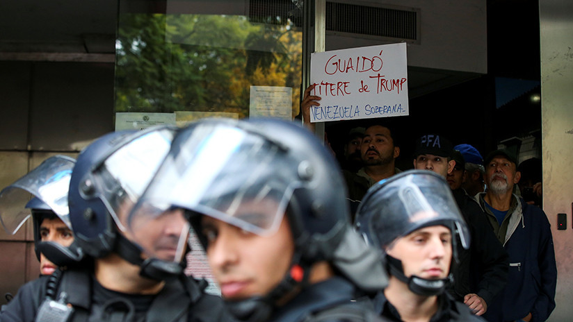 Un hombre sostiene un cartel que dice "Guaido, títere de Trump", dentro de la Embajada de Venezuela en Buenos Aires. 30 de abril de 2019.