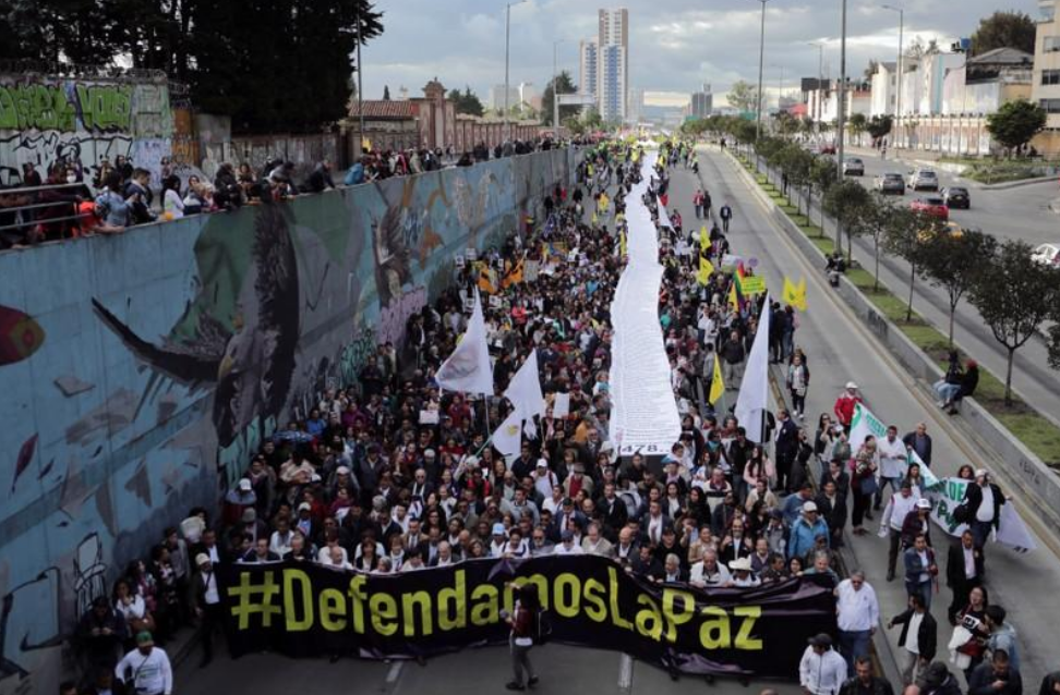 La gente sostiene una larga bandera blanca durante una protesta contra el asesinato de activistas sociales en Bogotá, Colombia
