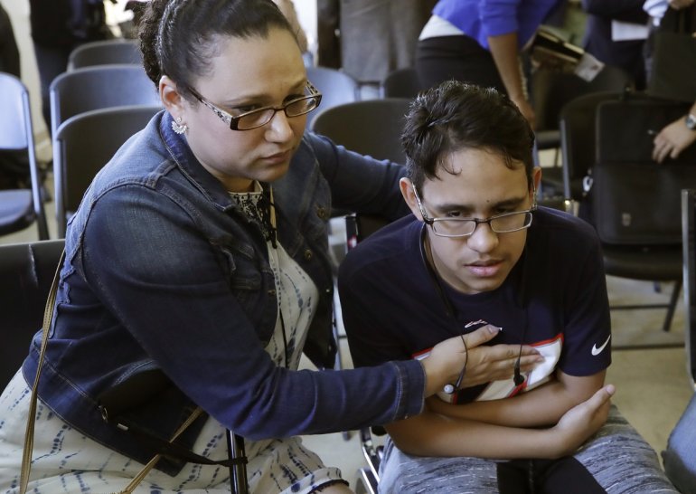 La hondureña Mariela Sánchez consuela a su hijo Jonathan, de 16 años, para quien buscan tratamiento médico en EEUU por su padecimiento de fibrosis quística, durante una conferencia de prensa el lunes 26 de agosto del 2019 en Boston