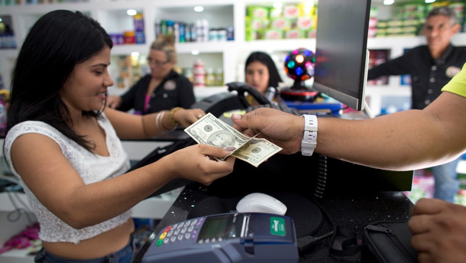 Un hombre paga sus compras con dólares estadounidenses en una tienda en Caracas, Venezuela