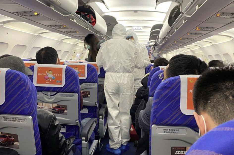 Trabajadores de salud con trajes protectores verifican la condición de un pasajero en un avión que acaba de aterrizar desde Changsha, una ciudad en una provincia vecina al centro del brote de coronavirus, en Shanghái, China