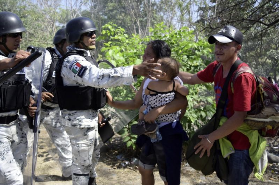 Miembros de la Guardia nacional detienen con escudos a migrantes