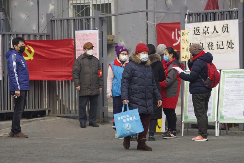 Residentes esperan para entrar a un punto de control que dice "punto de registro para personas que regresan a Beijing" en Beijing, China, hoy jueves 13/2/20