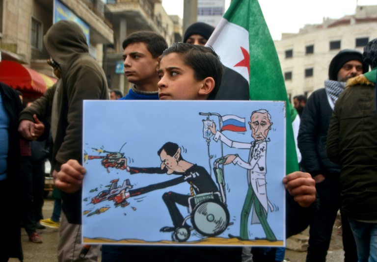 Una joven siria lleva un cartel con una caricatura de los presidentes ruso Vladimir Putin y sirio Bashar Al Asad durante una manifestación, el 21 de febrero en Idlib, en el noroeste de Siria