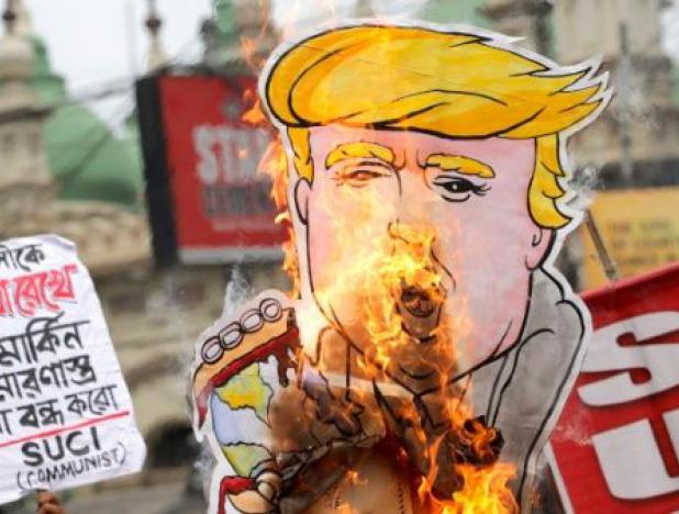 Activistas del Centro de Unidad Socialista de India (SUCI) queman un dibujo de Trump durante una protesta contra la visita del presidente de EEUU