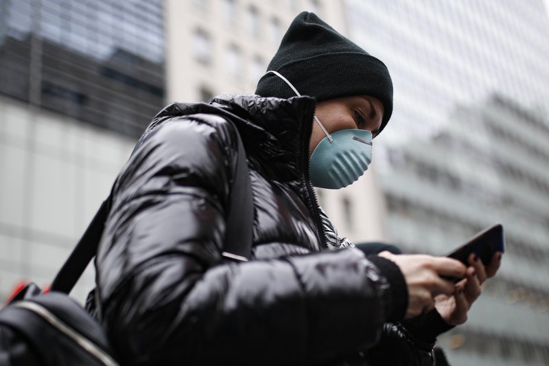 Una persona usa su teléfono celular, y también su máscara, para protegerse del coronavirus en Nueva York el 12 de marzo del 2020
