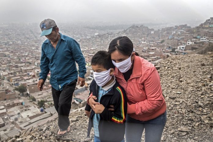 Una familia peruana ayuda al hijo para que asista a terapia diaria en un centro médico en las alturas de la barriada Vista Alegre del distrito de Comas en las afueras de Lima.