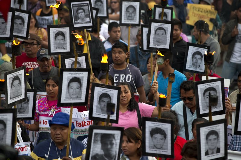 Familiares y activistas de 43 estudiantes normalistas desaparecidos en el estado de Guerrero portan sus retratos para exigir que no se cierre el caso en Ciudad de México