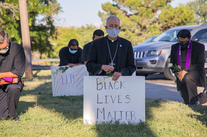 El obispo de la Diócesis de El Paso, Texas, Mark Seitz, se arrodilla junto a otros manifestantes, con un cartel de "Black lives Matter", en el Memorial Park de la ciudad
