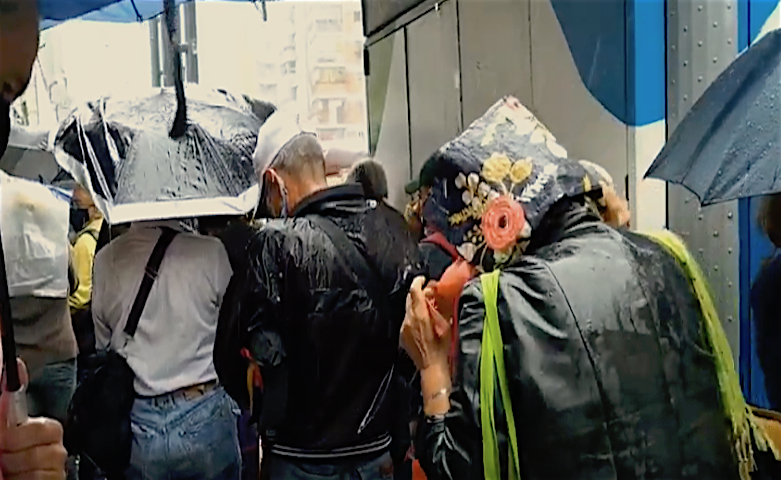 Jubilados de la Cancillería hacen cola bajo la lluvia para recibir bolsa de alimentos