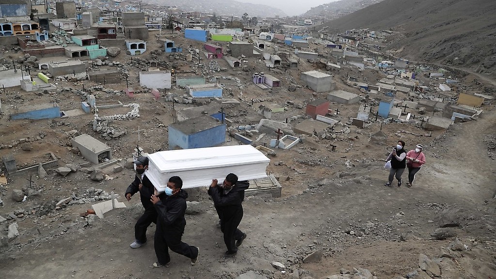 Los trabajadores del cementerio llevan el ataúd con una persona fallecida por covid-19 a un lugar de entierro en el cementerio en las afueras de Lima, Perú, el 26 de agosto. 2020.