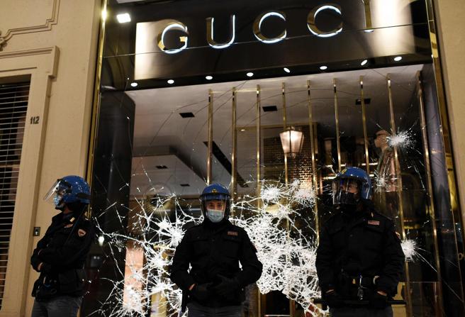Policías italianos ante el escaparate de la tienda de Gucci en Turín, atacada durante las protestas.