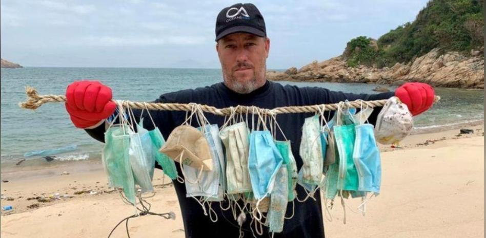 Gary Stokes, de la organización Oceans Asia, con una colección de mascarillas usadas encontradas en una playa de Soko