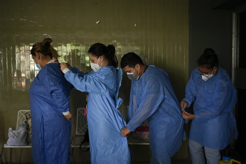 Médicos venezolanos poniéndose batas protectoras para hacer pruebas rápidas y gratuitas de Covid-19