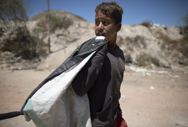 Ronaikel Brito, niño recogedor de basura, camina hacia su casa con un saco de cosas que recogió en el vertedero de Pavía, en Barquisimeto