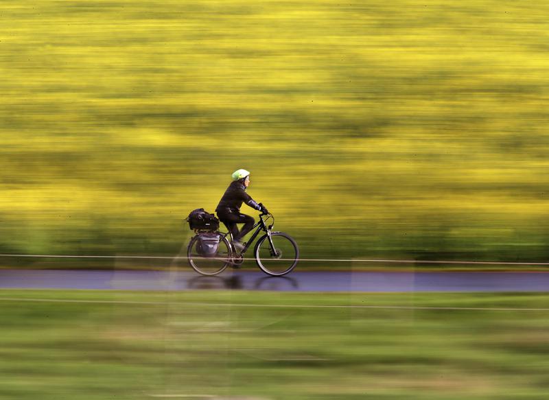 Mujer pasa en su bicicleta junto a un campo en Alemania