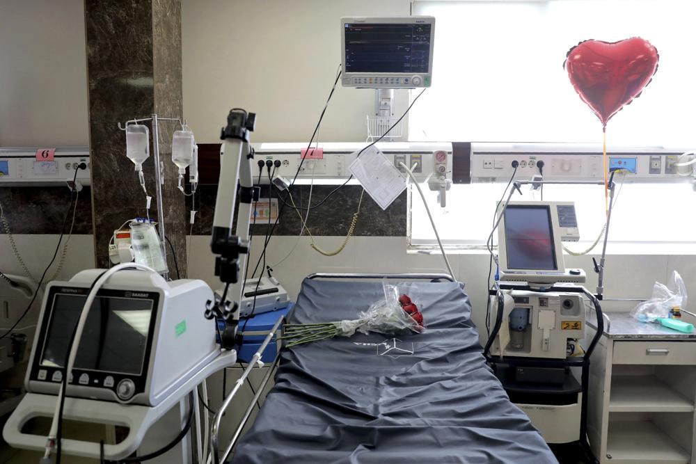 Un ramo de rosas y un globo en forma de corazón adornan la cama de un hombre que falleció de COVID-19 en la unidad de cuidados intensivos de hospital de Teherán