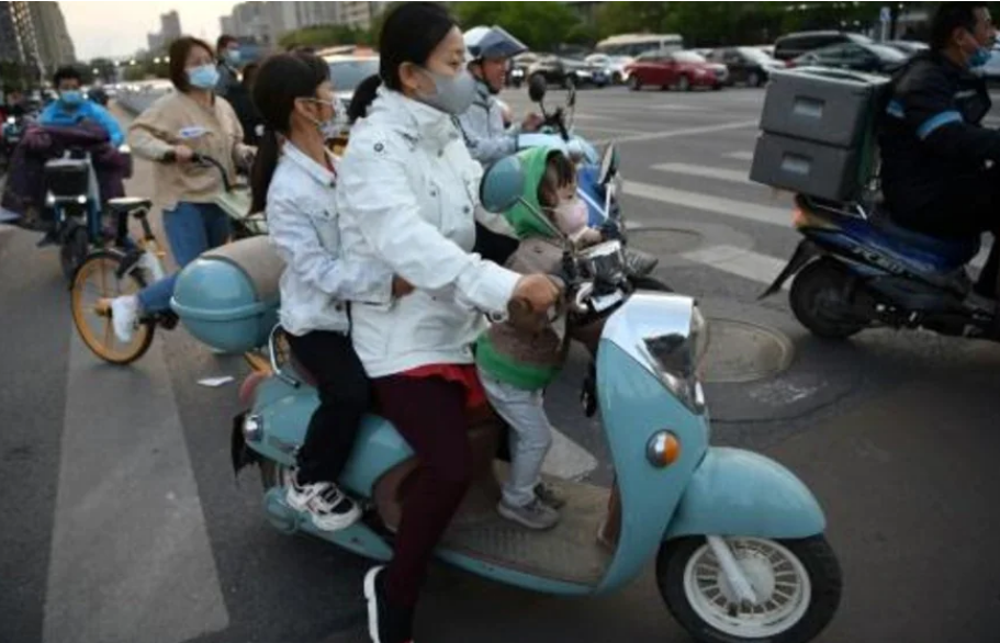 Una mujer lleva a dos niños en su motocicleta el 23 de abril de 2021 en Pekín