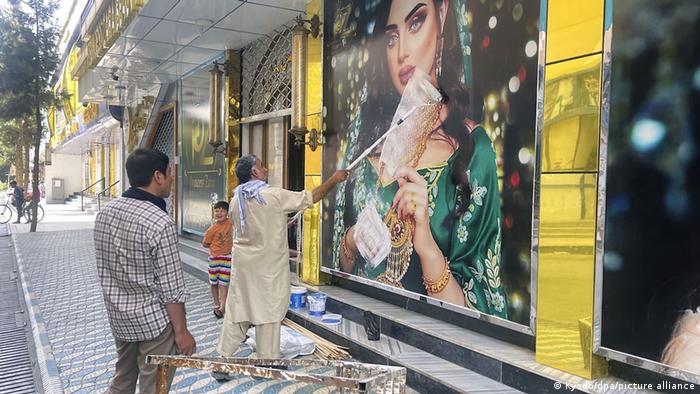 Hombres tapando con pintura las fotografías de mujeres en locales comerciales de Kabul