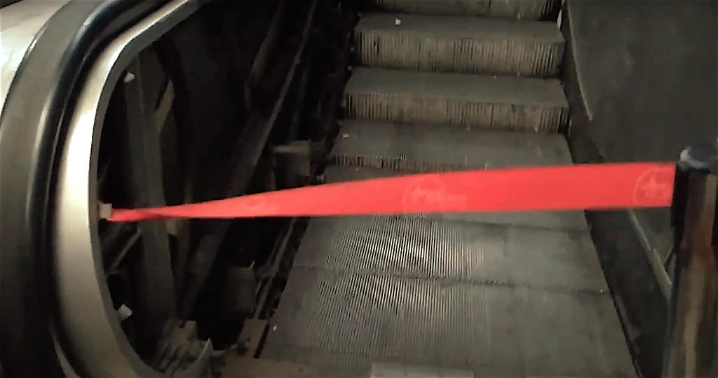 Un cordón rojo amarrado de forma improvisada a uno de los lados de la escalera mecánica